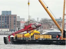  ?? THE ASSOCIATED PRESS ?? A helicopter is hoisted by a crane from the East River onto a barge Monday in New York. All five passengers aboard a helicopter that crashed into New York City’s East River were confirmed dead early Monday morning by a NYPD spokesman.