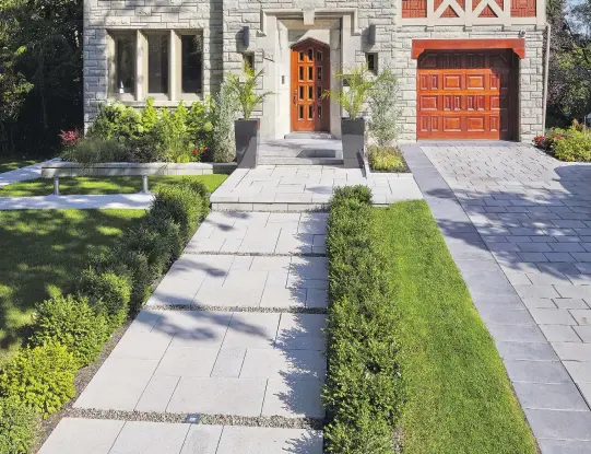  ??  ?? Pavers of various sizes, shapes and materials combine to meet different needs in the landscapin­g of this property — from the walkway, in which pavers are laid out in a specific pattern interspers­ed with rows of gravel, to the driveway. Low green shrubs...