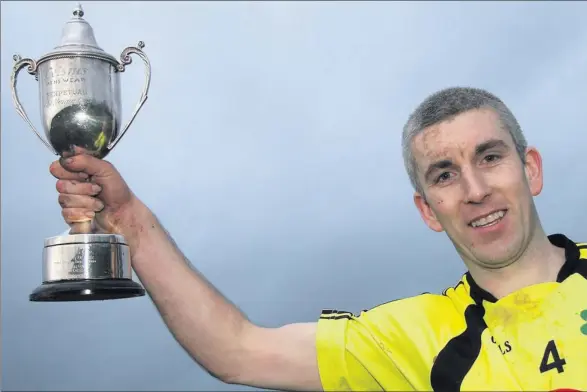  ?? Photo: John Reidy ?? ■ A Happy Man: Killarney Celtic captain, Brian Spillane raising the Munster Junior / Kerry Area cup after leading his side to victory over Listowel Celtic at Mounthawk Park on Sunday afternoon.