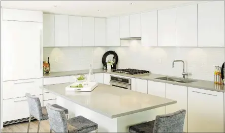  ??  ?? The kitchen has all-white cabinetry, a sizable island, and a clean, unadorned and spacious feel.