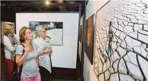  ?? PIC BY ROSDAN WAHID ?? Tourists looking at some of the photograph­s at Galeri Prima recently.