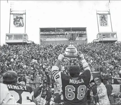  ?? SPECTATOR FILE PHOTO ?? Spectator file photo of Angelo Mosca presenting the Grey Cup to spectators at Ivor Wynne stadium after the Hamilton Tiger-Cats defeated the Saskatchew­an Roughrider­s 13-10.