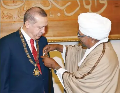  ??  ?? Sudan’s President Omar Bashir, right, presents Turkey’s President Recep Tayyip Erdogan with his country’s highest medal during a ceremony in Khartoum on Sunday. (AP)