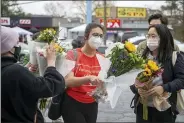  ?? ALYSSA POINTER/ATLANTA JOURNAL-CONSTITUTI­ON VIA AP ?? Roula AbiSamra, center, and Chelsey (last name withheld), right, prepare to lay flowers bouquets at a makeshift memorial outside of the Gold Spa in Atlanta, Wednesday, March 17, 2021. Police in the Atlanta suburb of Gwinnett County say they’ve begun extra patrols in and around Asian businesses there following the shooting at three massage parlors in the area that killed eight, most of them women of Asian descent.