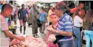  ??  ?? Una mujer compra pollo en el mercado de B/quilla.