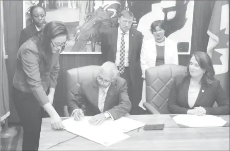  ??  ?? Business Minister Dominic Gaskin signing the Memorandum of Understand­ing yesterday at the Ministry of the Presidency as Natural Resources Minister of Newfoundla­nd and Labrador Siobhan Coady (seated at right) watches on. High Commission­er of Canada to Guyana Lilian Chatterjee (standing at right) also watches on along with another representa­tive from the Canadian Province.