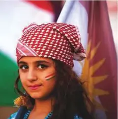  ?? AFP ?? A young Syrian Kurd carries the Kurdish flag in Qamishli during a gathering.