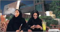  ?? HASSAN AMMAR/THE ASSOCIATED PRESS ?? A Saudi woman smokes tobacco from a waterpipe as her friend looks at her cellphone in a coffee shop in Jiddah, Saudi Arabia.