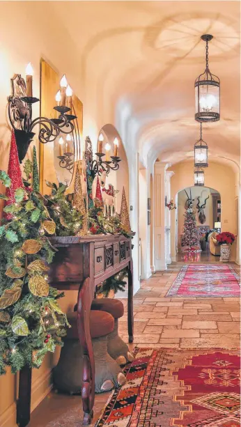  ??  ?? The entry hall in Meredith and Mike Howard’s home leads to one of their Christmas trees. They decorate two — one whimsical and one with cherished ornaments.