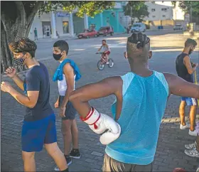  ??  ?? Boys wear masks as they train at sunset in Havana.