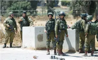  ?? (Mussa Qawasme/Reuters) ?? SOLDIERS GATHER at the scene of a stabbing attack yesterday near the Arroub refugee camp in the West Bank.