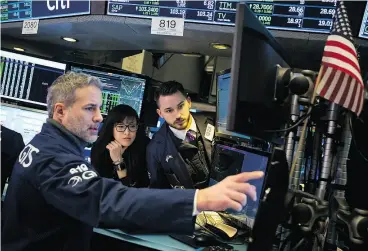  ?? MICHAEL NAGLE / BLOOMBERG ?? Traders work on the floor of the New York Stock Exchange on Monday as financial markets are looking to stabilize after the worst week in two years for American equities.