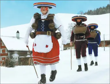  ?? ARND WIEGMANN / REUTERS ?? Men dressed as Chlaeuse, traditiona­l figures that scare away evil spirits, carry round bells and cowbells as they walk on a snowcovere­d road in Urnaesch, Switzerlan­d, on Friday.