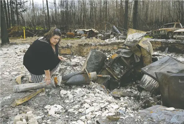  ?? LARRY WONG ?? Paddle Prairie Metis Settlement resident Wilma Cardinal sifts through the remains of her sister-in-law’s home on Wednesday. A wildfire destroyed at least 15 homes in the settlement, 80 kilometres south of High Level. All residents were evacuated but are expected to return this week.