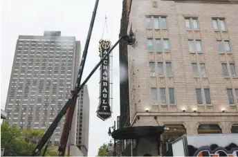  ?? PHOTOS ADIL BOUKIND LE DEVOIR ?? Ci-dessus : l’enseigne du célèbre magasin Archambaul­t a été retirée sous la pluie, mercredi matin, de l’immeuble à l’angle des rues Berri et Sainte-Catherine Est, le temps de se refaire une beauté. À gauche : d’anciens employés se sont réunis une dernière fois à la place Émilie-Gamelin, le 19 mai.