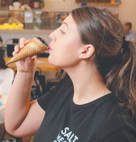  ?? Picture: RICHARD GOSLING ?? Waitress Sarah Clark quaffs a coffee from a cone at Salt Meats Cheese in Surfers Paradise.