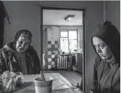  ?? ?? Iryna Abramova, left, prepares food April 22 with her neighbor Iryna Hres in remembranc­e of Hres’ mother. The elderly woman had died in early March during the occupation.