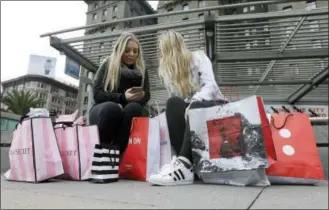 ?? THE ASSOCIATED PRESS ?? Maddy, left, and her friend Maggie sit with their shopping bags Nov. 25 at Union Square in San Francisco. The holiday shopping season is losing some of its power in the year’s sales. November and December now account for less than 21 percent of annual...