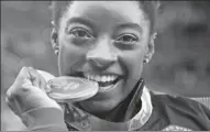  ?? DMITRI LOVETSKY / AP ?? Simone Biles of the US bites her medal after winning the individual all-around gymnastics final on Thursday.