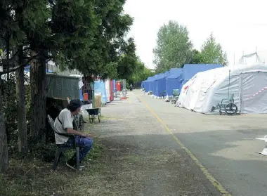  ?? ?? Crollo e rinascita In alto la fila degli sfollati nell punto di raccolta degli aiuti, sotto la tendopoli della Protezione civile