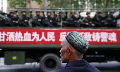  ?? Photograph:
China Stringer Network/Reuters ?? A truck carrying paramilita­ry policemen passes a Uighur man during an anti-terrorism oath-taking rally in Urumqi, Xinjiang.