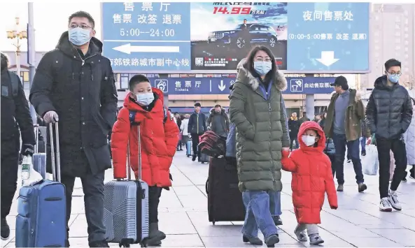  ?? FOTO: AP ?? Reisende mit Mundschutz gehen am Montagnach­mittag zu ihren Zügen auf dem Bahnhof in Peking.