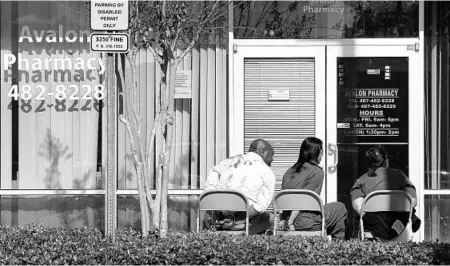  ?? JACOB LANGSTON/STAFF PHOTOGRAPH­ER ?? Valentine Okonkwo, left, and 2 employees of Avalon Pharmacy sit outside in handcuffs Thursday while authoritie­s search the store in a shopping center on South Avalon Park Boulevard in east Orange. Drug-traffickin­g suspects told authoritie­s Okonkwo...