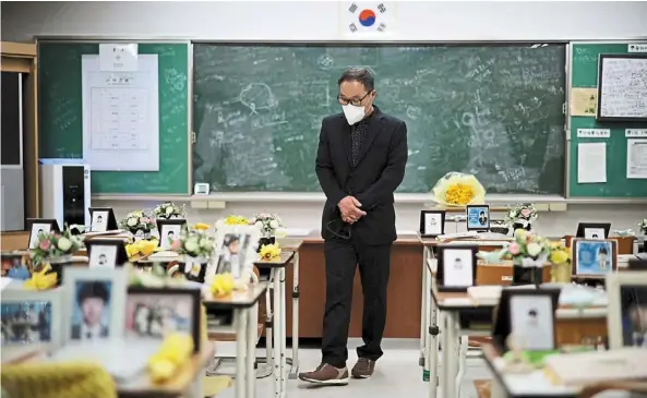 ?? ?? Solemn: A man looking around a replicated classroom of students who died in the sunken Sewol ferry disaster that killed 304 people, mostly school students, in Ansan, South Korea. — Reuters