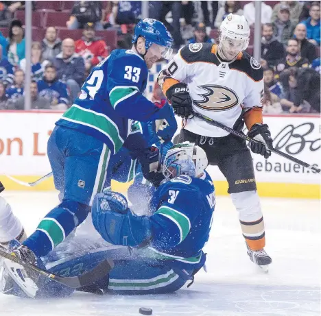  ?? JONATHAN HAYWARD/THE CANADIAN PRESS ?? Vancouver Canucks centre Henrik Sedin collides with goaltender Anders Nilsson with Anaheim Ducks centre Antoine Vermette in pursuit of the puck in the first period on Tuesday night at Rogers Arena. Nilsson was pulled after allowing four goals on 19...