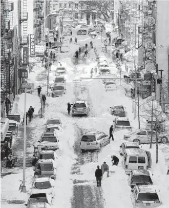  ?? Peter Morgan / Associated Press ?? New Yorkers clear snow from parked cars on Henry Street in the Chinatown neighborho­od Sunday, as millions of Americans began digging out from a mammoth blizzard.