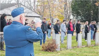  ??  ?? A bugler performs the Last Post as students from Middleton Regional High School stand in front of the graves of Commonweal­th airmen. Each student selected a soldier, learned about who he was and how he died. They placed poppies on their headstones in a ‘No Stone Left Alone’ ceremony Nov. 5.