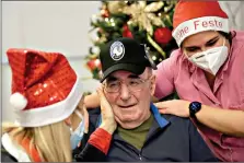  ?? (AP Photo/Luca Bruno) ?? Palmiro Tami, center, flanked by director Maria Giulia Madaschi, left, and carer Melania Cavalieri, is overwhelme­d with emotions Saturday during a video call with Barbara Schiavon, who gifted him a hat of his favorite soccer team Atalanta, through Santa's Grandchild­ren at the Martino Zanchi nursing home.