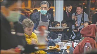  ?? (File Photo/AP/Emilio Morenatti) ?? Waiters w earing m asks serve food and drink in a terrace outside Mestalla stadium on March 10, 2020, during the Champions League round of 16 second leg soccer match between Valencia and Atalanta in Valencia, Spain. The match was played in an empty stadium because of the coronaviru­s outbreak.