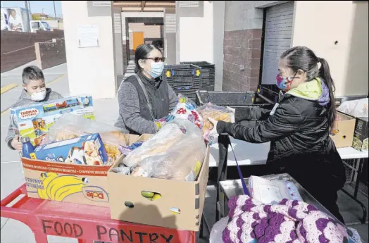  ?? K.M. Cannon Las Vegas Review-Journal @KMCannonPh­oto ?? Roxy Hernandez, right, loads food Thursday for Jeremy Galindo, 10, and his mother, Delmy Galindo, at the Hands of Hope Food Pantry at Catholic Charities of Southern Nevada. The pandemic has caused heavy demand for Nevada’s nonprofits.