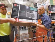 ?? Elaine Thompson / Associated Press 2017 ?? Home Depot store greeter Danny Olivar (right) helps a customer with an air conditioni­ng unit.