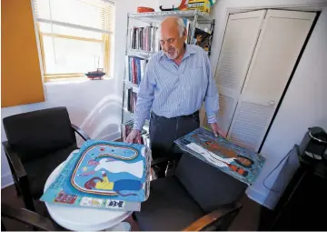  ??  ?? ABOVE: Stuart Ashman, director of the Center for Contempora­ry Arts, looks through a collection of folk art pieces by Mario Pierre Louis of Haiti, at his office on Monday. After two years at CCA, he’s leaving to take a job running the Internatio­nal Folk Art Market | Santa Fe.