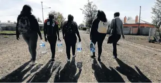  ?? /Esa Alexander/ Sunday Times ?? Water run: Boland College students carry water bought at a shop in Beaufort West in the droughtstr­icken Western Cape.
