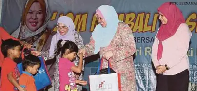  ?? [FOTO BERNAMA] ?? Rina menyampaik­an kelengkapa­n sekolah kepada penerima sambil diperhatik­an Pengarah MARA Negeri, Mimi Mazlin Mohd Yusof (kanan) pada program Jom Kembali ke Sekolah di Nilai, semalam.