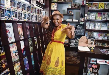  ?? HYOSUB SHIN / HSHIN@AJC.COM ?? Comic book artist Afua Richardson strikes a superhero pose surrounded by the inventory at My Parents’ Basement, a restaurant/comic book store in Avondale Estates.