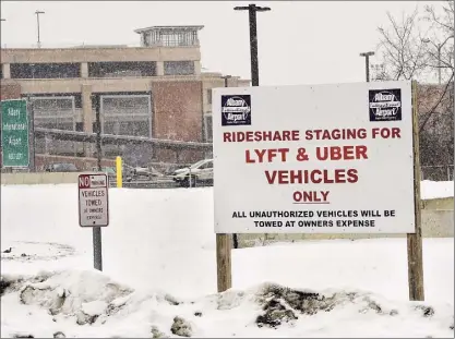  ?? Photos by Lori Van Buren / Times Union ?? The Albany Internatio­nal Airport is seen beyond a sign at the ride-sharing staging lot for Lyft and Uber vehicles on Monday in Colonie. Most workers at Uber, Lyft, Doordash, Postmates, and Instacart work less than 15 hours a week, according to new data from the New York Coalition for Independen­t Work.