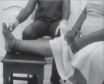  ??  ?? A health worker administer­ing foot care to a filaria patient.