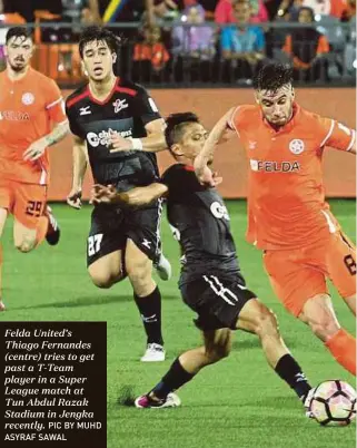  ?? PIC BY MUHD ASYRAF SAWAL ?? Felda United’s Thiago Fernandes (centre) tries to get past a T-Team player in a Super League match at Tun Abdul Razak Stadium in Jengka recently.