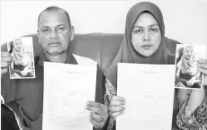  ??  ?? Mohd Samuddin Mat Salleh and his wife Salina Deraman hold up a police report and photo of their daughter Mirsya Saffiyah who went missing more than three months ago. - Bernama photo