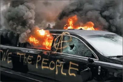  ?? The Associated Press ?? FIRE: A parked limousine burns during a demonstrat­ion after the inaugurati­on of President Donald Trump on Friday in Washington. Protesters registered their anger against the new president Friday in a chaotic confrontat­ion with police who used pepper...