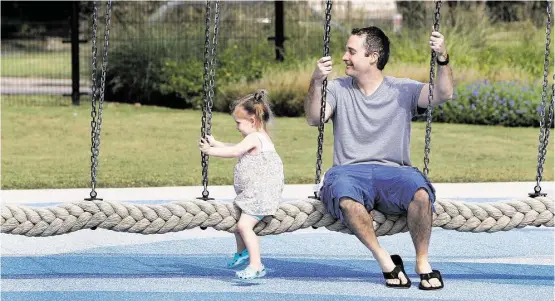  ?? Steve Gonzales photos / Houston Chronicle ?? Travis Corgey swings with his 2 year-old daughter Zoe in Cinco Ranch’s Exploratio­n Park. Nature-themed parks are growing in master-planned communitie­s.