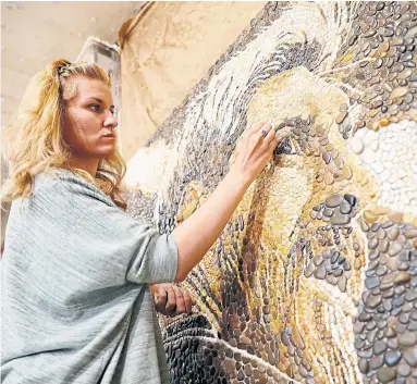  ?? EUGENE HOSHIKO/THE ASSOCIATED PRESS ?? Russian artist Anna Solnechnay­a is in her Kazan workshop with one of her pebble mosaics, this one depicting Argentina star Lionel Messi. The Argentines open their World Cup on Saturday against Iceland.