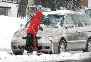  ?? GENE WALSH — DIGITAL FIRST MEDIA ?? A heavy snow falls in Lansdale Wednesday as a woman works to dig out her vehicle along Broad Street.