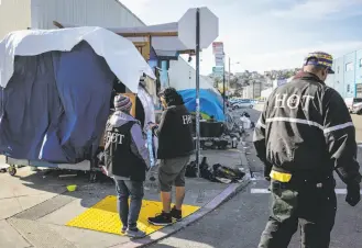  ?? Gabrielle Lurie / The Chronicle ?? Members of the Homeless Outreach Team stop while they work at an encampment on S.F.’s Carolina Street, where they are attempting to get people into shelters or treatment programs.