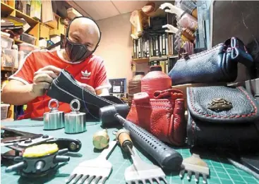  ?? — THOMAS YONG/ The Star ?? Hard at work: Leong sewing a pouch at his workshop. He also makes handbags from leather scraps.