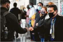  ??  ?? Francisco Rivera, a staff member at Booker T. Washington High School, greets students with fist-bumps on Monday.